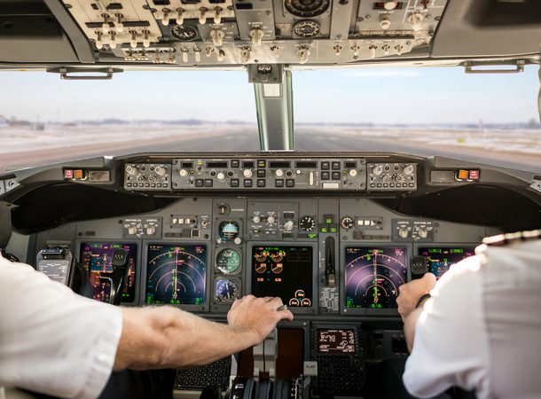 Captain is pulling an aircraft throttle, while first officer is piloting and taking off. Pilots are sitting in Boeing 737-800.